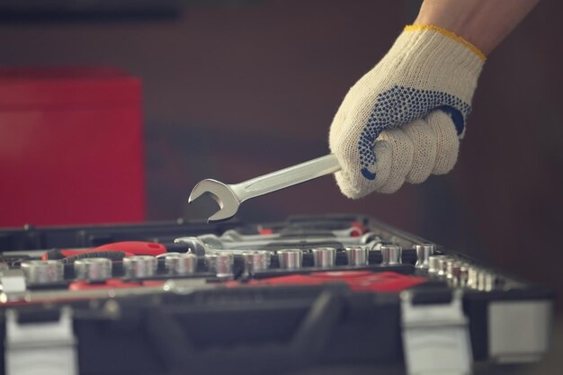 Technician inspecting car battery with wrench for signs of failure.