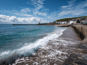 Coastal beach with waves crashing and seaside village in the background.
