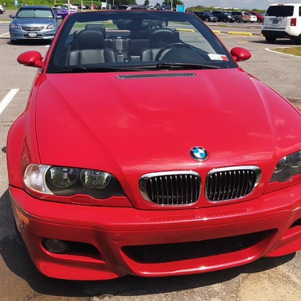 Red BMW convertible parked in lot for sale.