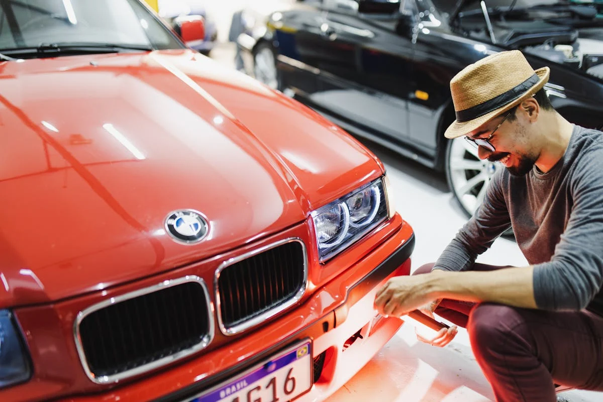 Skilled technician inspecting a red BMW for repairs at Senshine Autos.