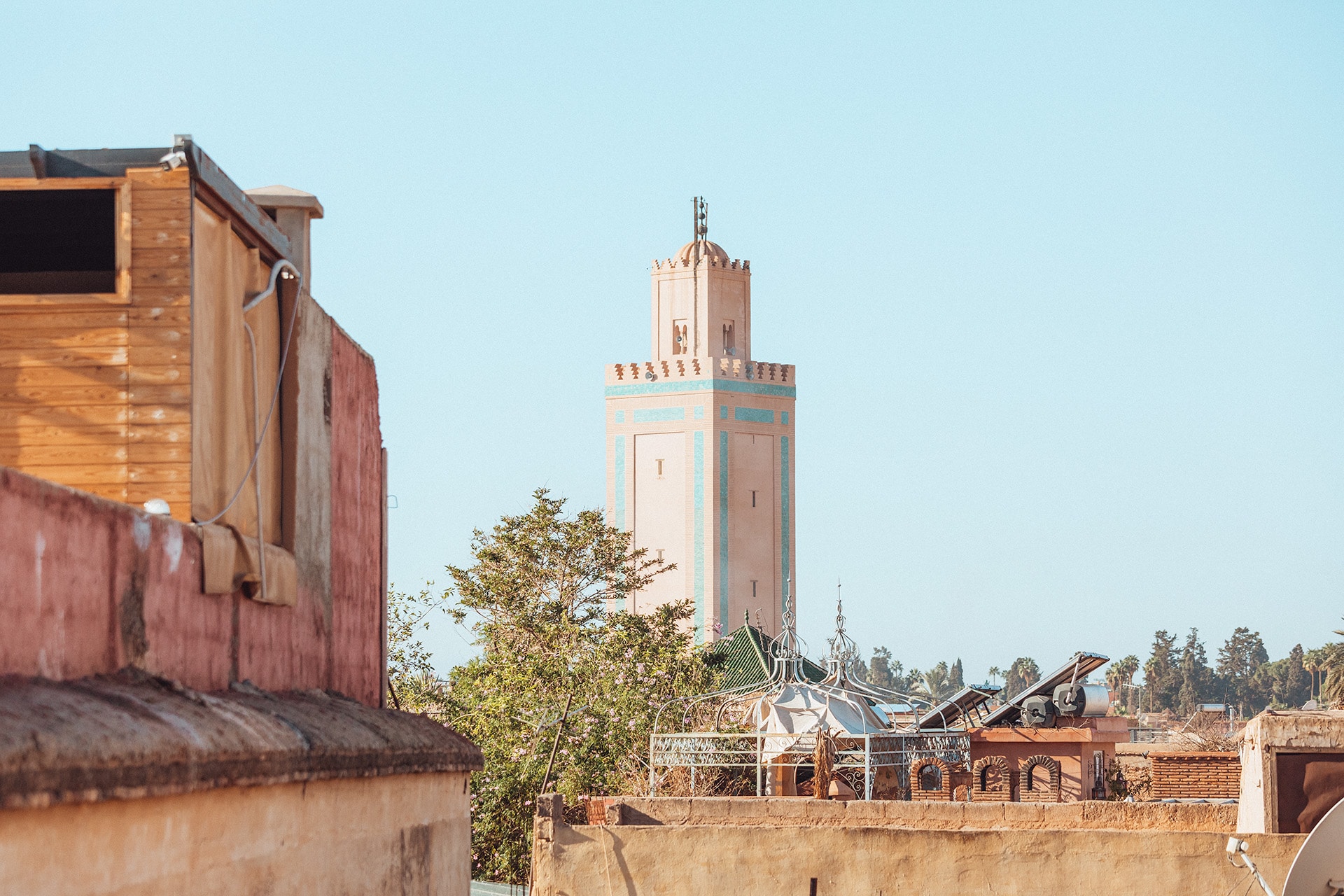 Rooftop views in Marrakech, a pale pink and blue tower against a pale blue sky