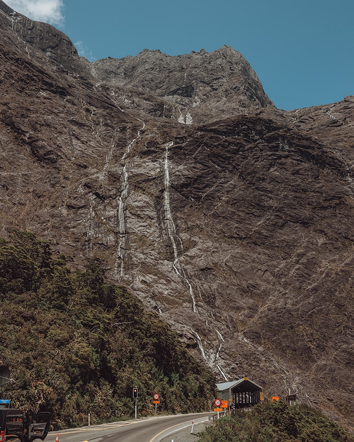 A tall grey mountain with small waterfalls running down it. The Homer Tunnel, Milford Sound.