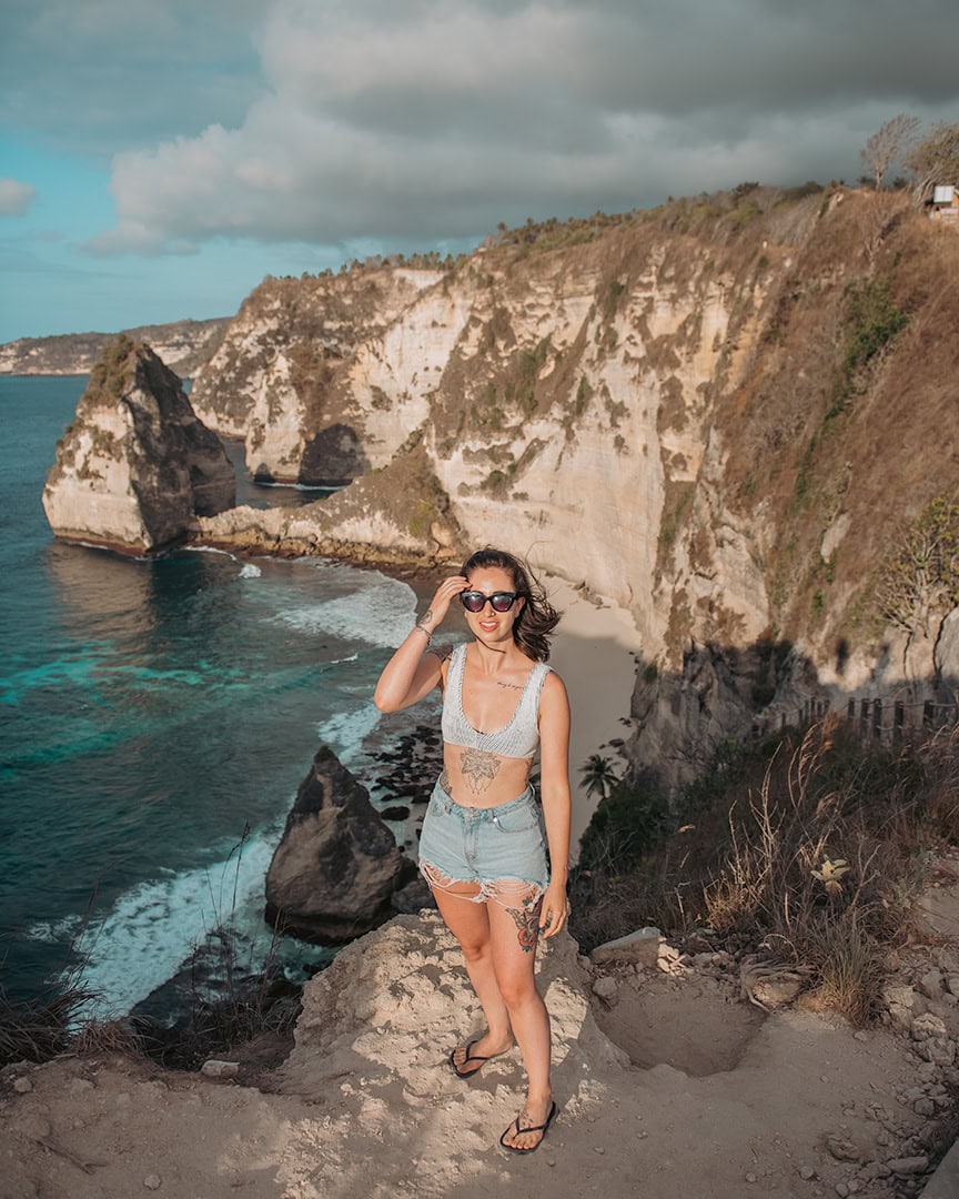 A woman standing on a viewpoint that looks out over dramatic cliffs and turquoise waters of Diamond Beach.