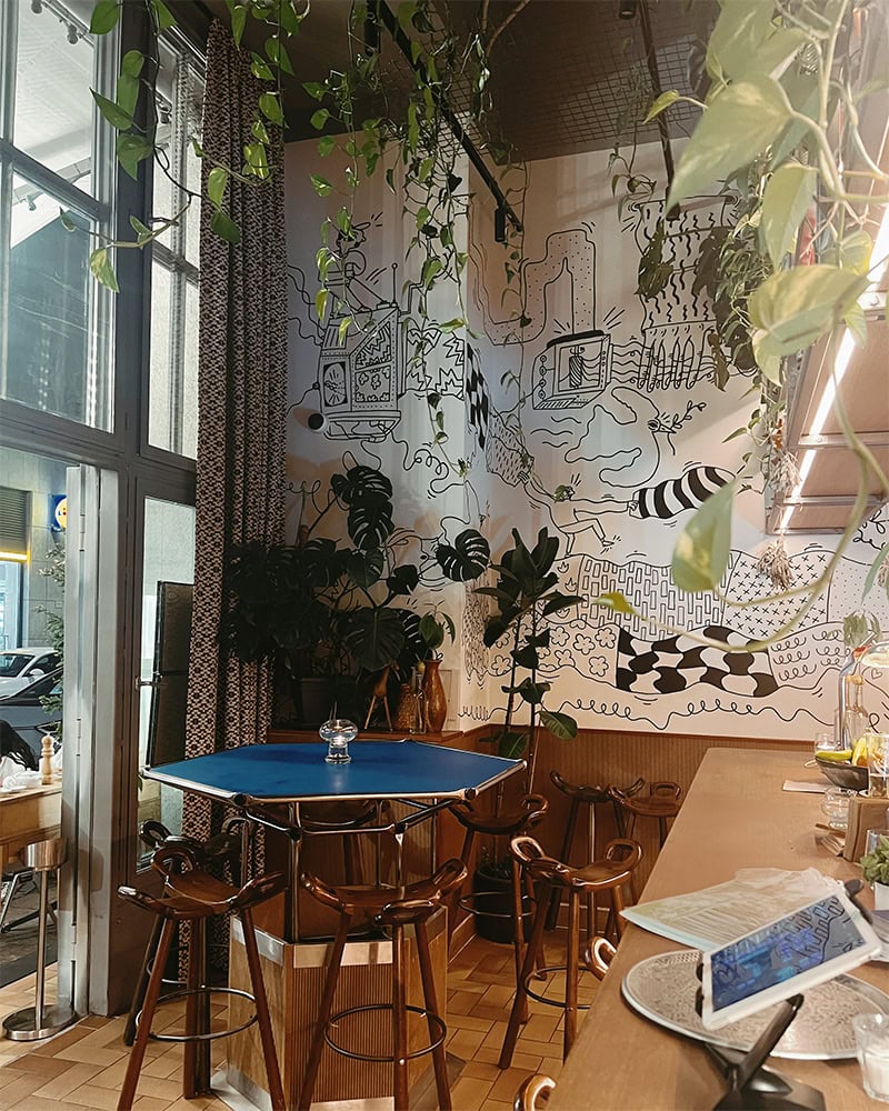Interior of a Middle Eastern restaurant with high ceilings, plants, and artistic wall decor. Goli, Budapest has some great vegan options.