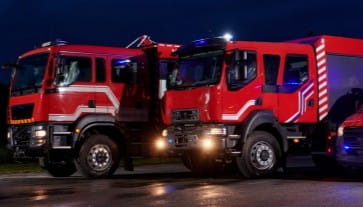 Fire trucks at night with emergency lights on, ready for response.