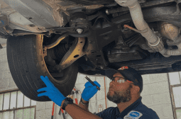 Mechanic inspecting vehicle underside during auto repair service.