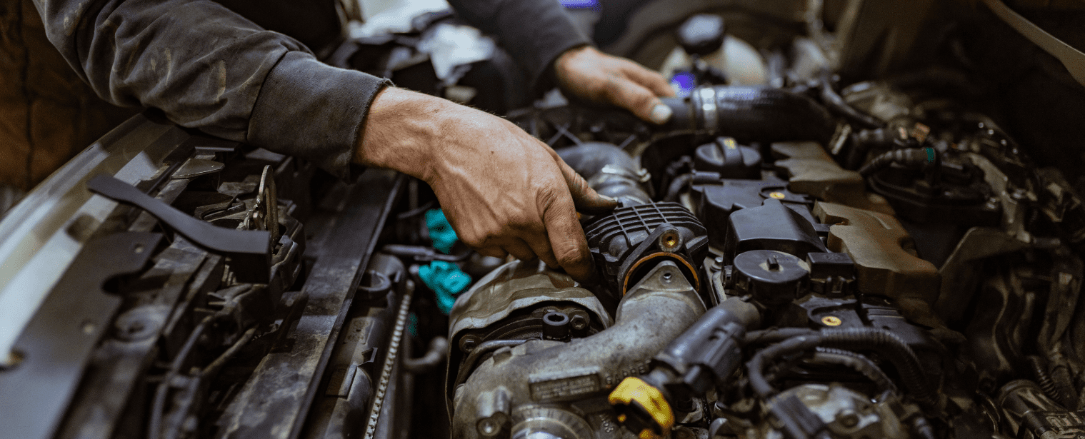 Auto repair technician inspecting engine components.
