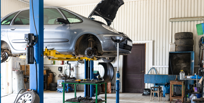 Auto repair shop with a car on lift for preventive maintenance services in Suitland, MD.