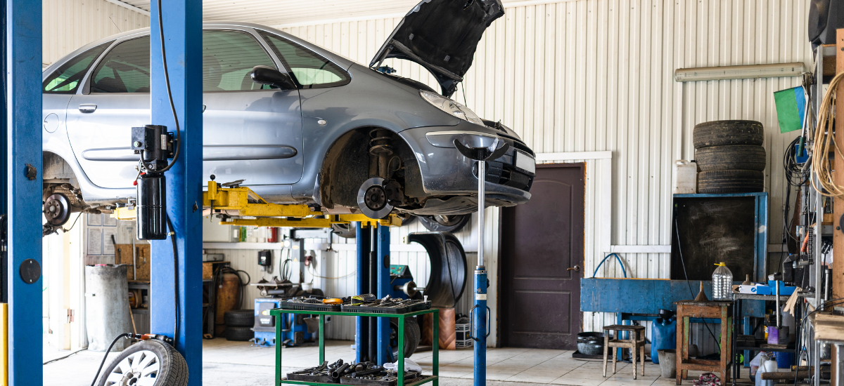 Auto repair shop with a car on lift for preventive maintenance services in Suitland, MD.