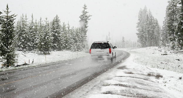 Snowy winter road conditions impacting vehicle performance and safety.