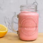 Fresh strawberry lemon smoothie in a mason jar with a lemon wedge on a wooden surface, perfect for healthy eating, fruit smoothies, and summer beverages.