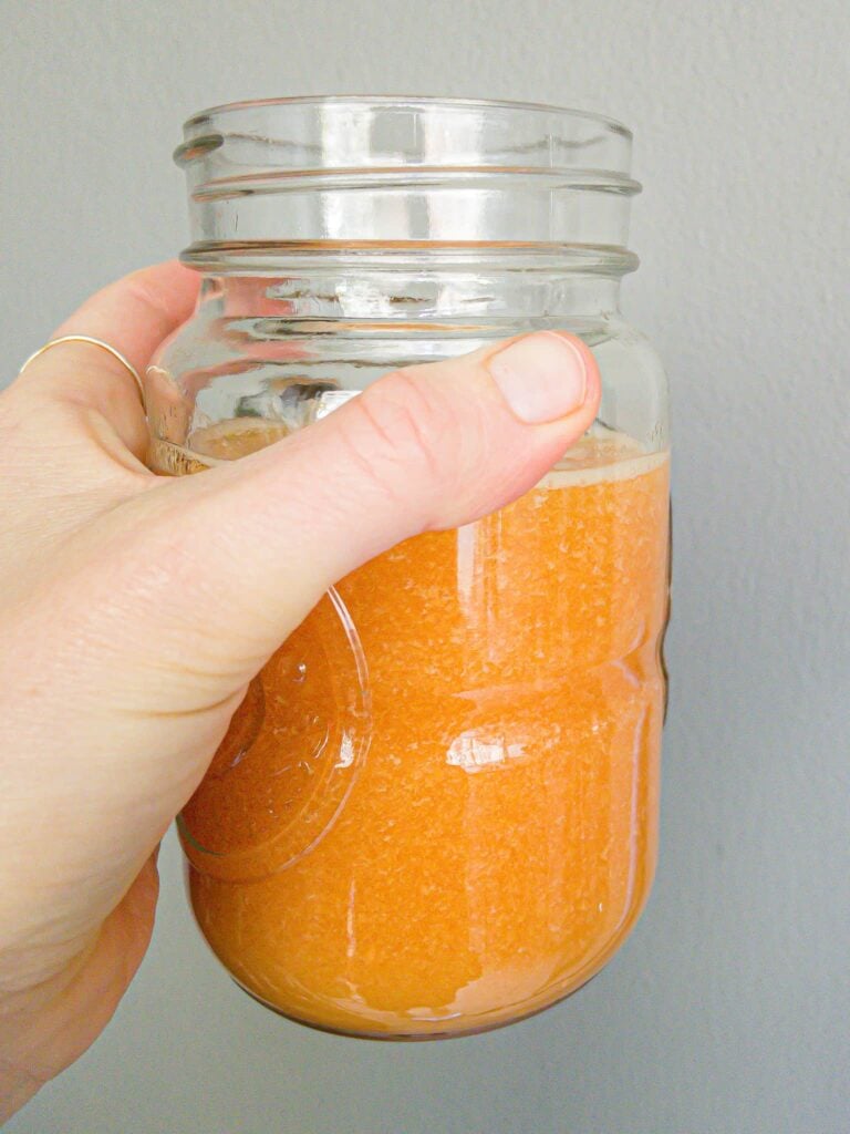 Freshly made orange sugar scrub in a clear jar, perfect for skincare and exfoliation, featuring natural ingredients like sugar and citrus for glowing skin.