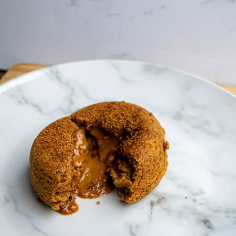 Crispy vegan fried delicious stuffed with melty cheese and savory caramelized onions on white marble plate.
