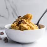 Creamy chocolate chip cookie dough ice cream served in a white bowl with a spoon, perfect for dessert or a sweet treat.