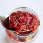 Fresh homemade strawberry jam in a glass jar with a metal spoon, highlighting natural fruit preserves.