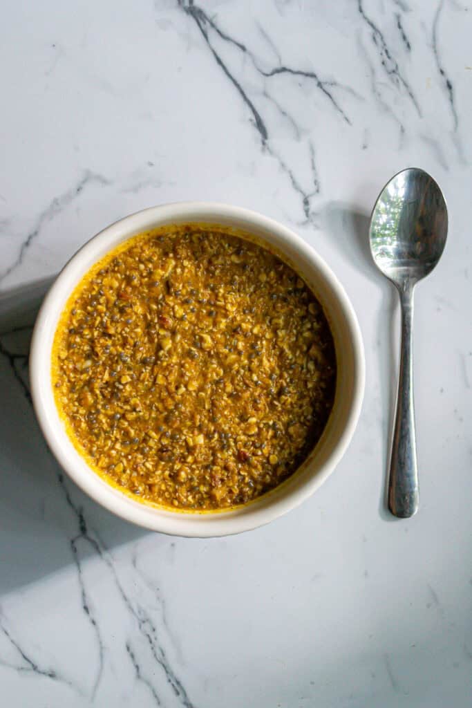 Creamy lentil soup with herbs in a white bowl on a marble surface.