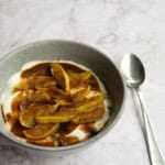 Savory egg and mushroom dish topped with rich gravy in a gray bowl with a silver spoon on a marble surface.