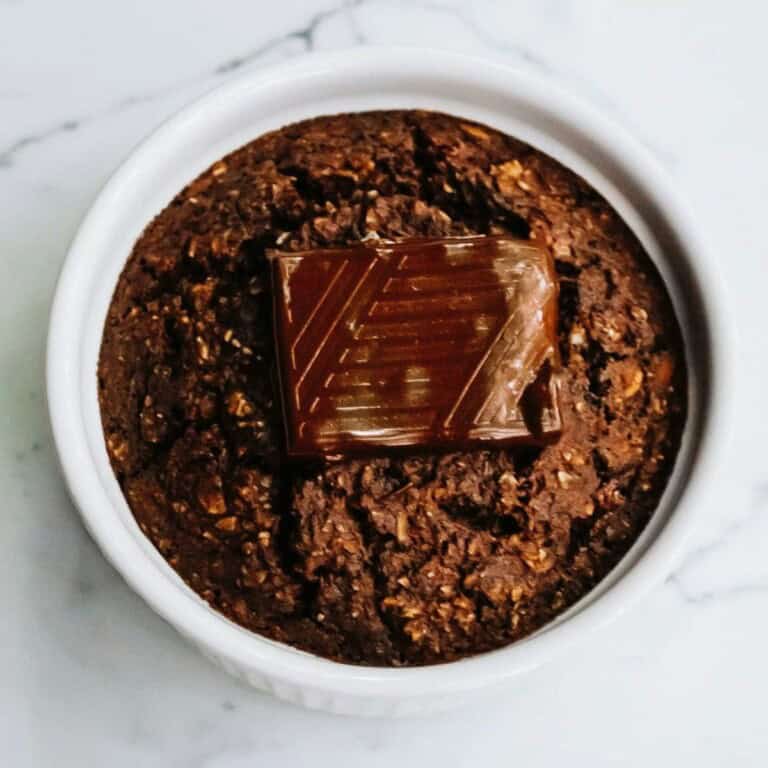 Rich chocolate brownie with a glossy chocolate piece on top, served in a white ramekin. Perfect for dessert lovers seeking indulgent, homemade-style sweet treats. Ideal for baking enthusiasts and chocolate fans.