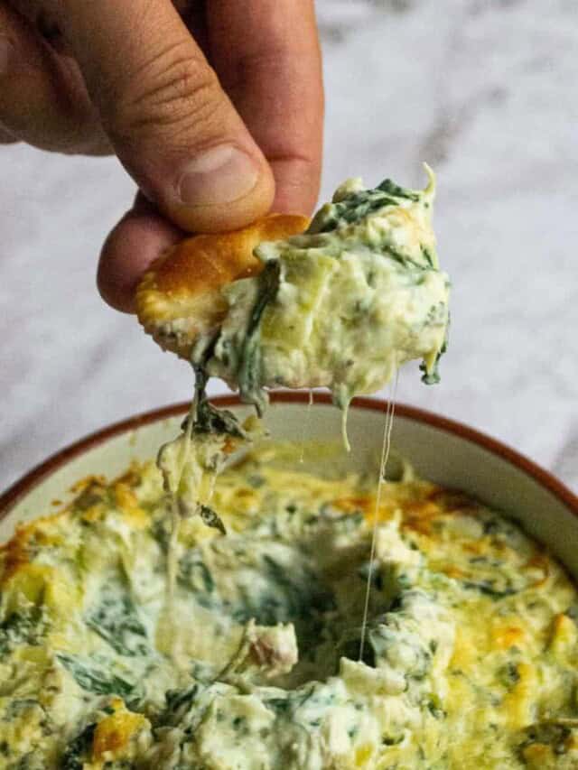 Healthy spinach artichoke dip on a cracker.
