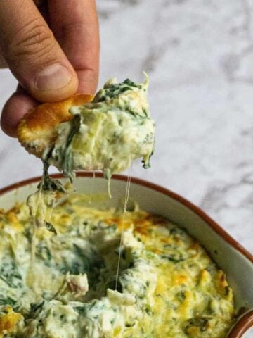 Healthy spinach artichoke dip on a cracker.