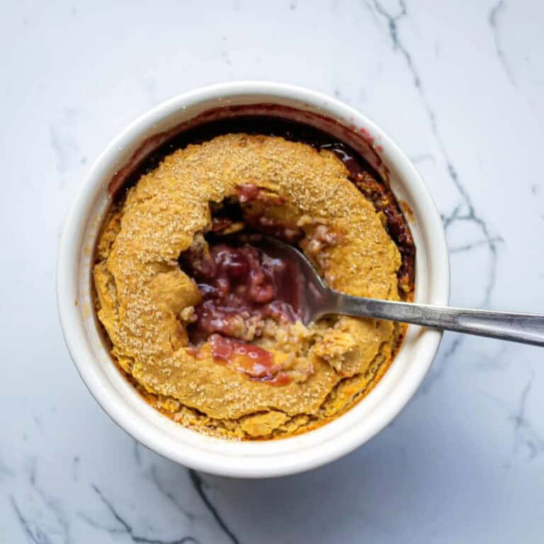 Savory cherry cobbler in a white ramekin with a spoon, homemade fruit dessert, simple fresh food, sweet and tart cherry filling, baked crust topping, delicious seasonal fruit dessert, easy dessert recipe, perfect for summer or fall, healthy fruit-based treat, comfort food dessert, family favorite dessert.