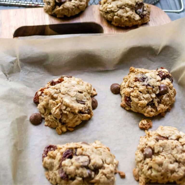 Homemade oatmeal chocolate chip cookies on parchment paper with a wooden background, freshly baked cookie close-up, delicious and wholesome snacks, perfect for snacks or desserts, Simply Fresh Foodie.