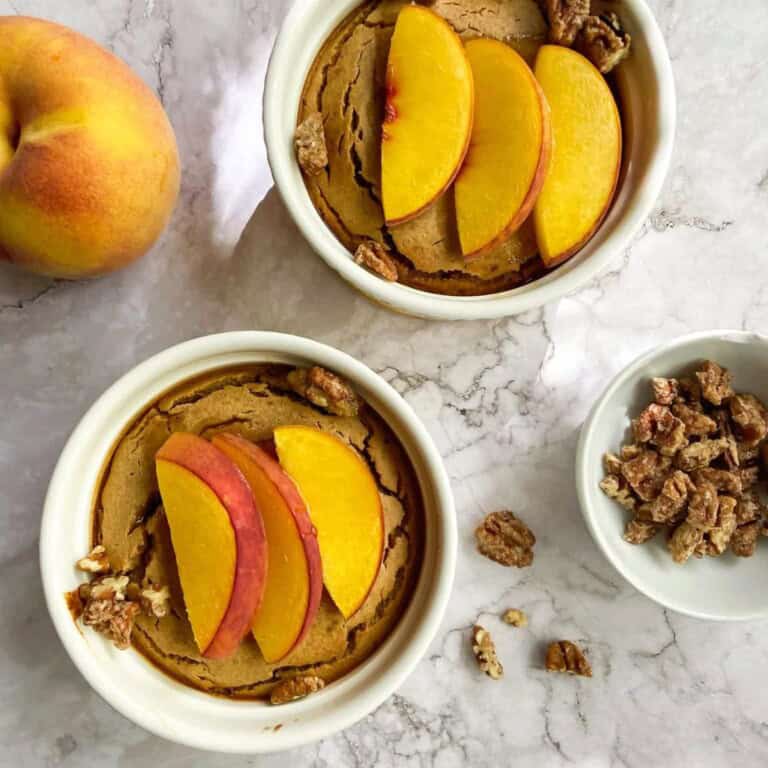 Peach and oat crumble dessert in ramekins topped with peach slices and walnuts, served on a marble surface, showcasing healthy fruit-based dessert options from Simply Fresh Foodie.