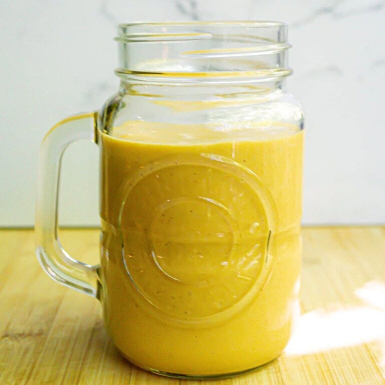 Creamy yellow smoothie in a glass jar with handle, fresh and healthy, perfect for breakfast or snack, featuring natural ingredients and vibrant color.