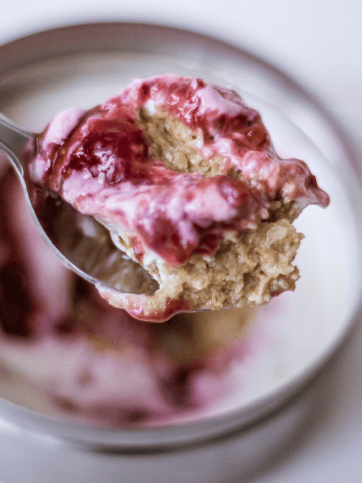Creamy strawberry oatmeal pie filling in a spoon with a pink berry sauce swirl, served in a jar. Perfect for a healthy breakfast or dessert, featuring fresh strawberries and hearty oats.