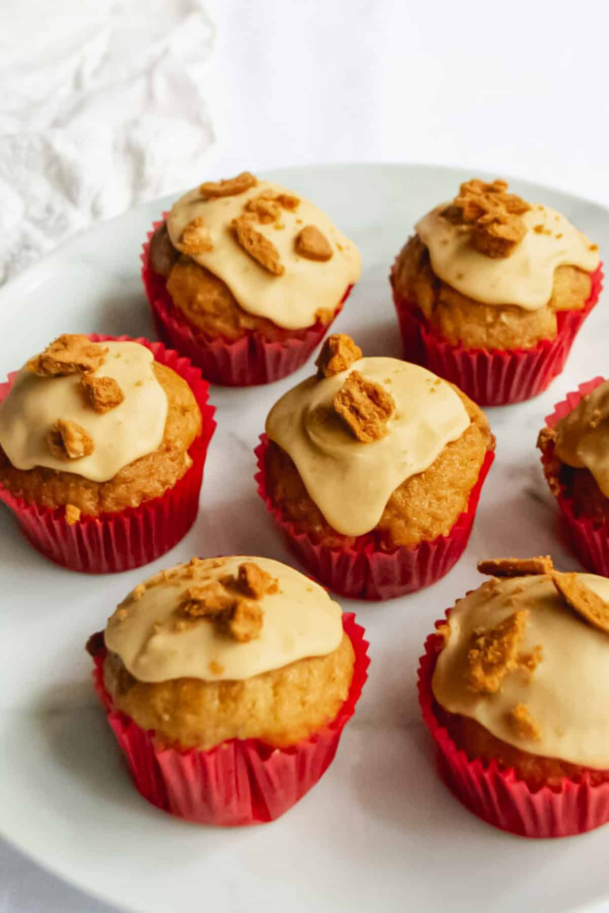 Cream cheese frosting topped with crumbled cookies on red paper cupcake liners, delicious homemade muffin cupcakes.