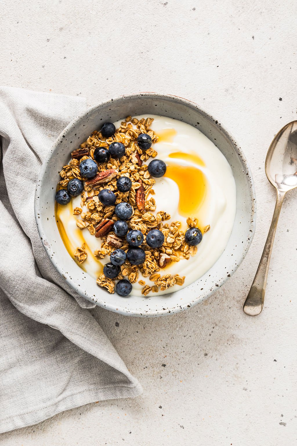 Overhead view of vegan soy yoghurt with granola, honey and blueberries on top.