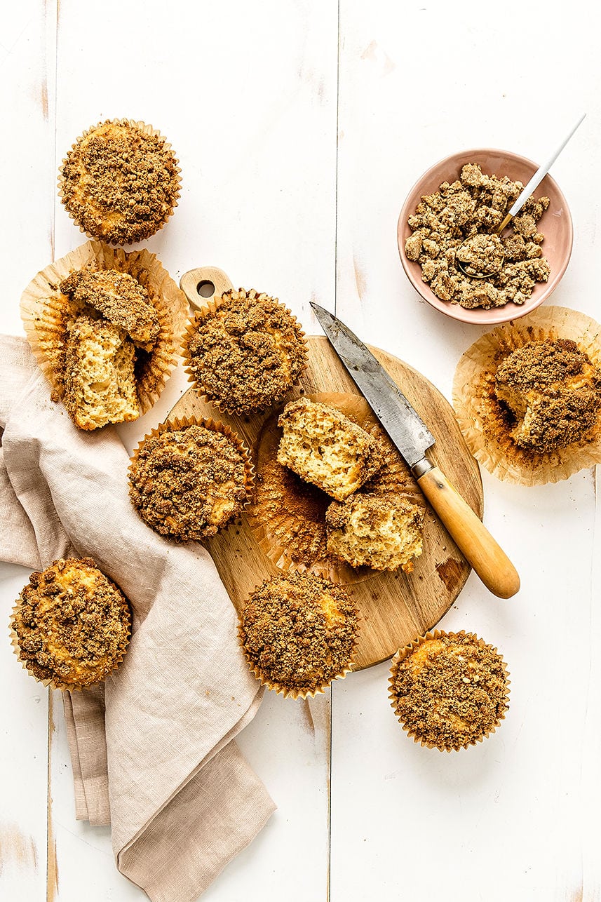 Overhead view of coffee cake muffins with crumb topping on a wooden cutting board.