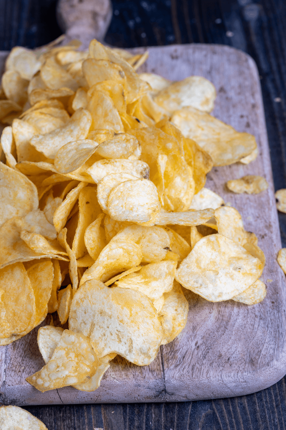Potato crisps on a wooden cutting board.