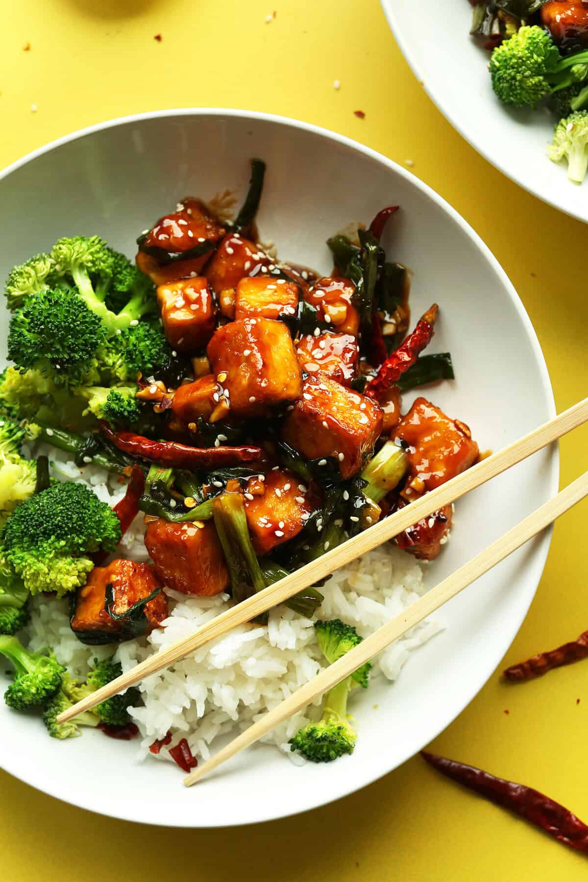 Sweet and spicy tofu stir-fry with broccoli, red chili peppers, and sesame seeds served over white rice, highlighting healthy vegetarian meal options and Asian-inspired cuisine.