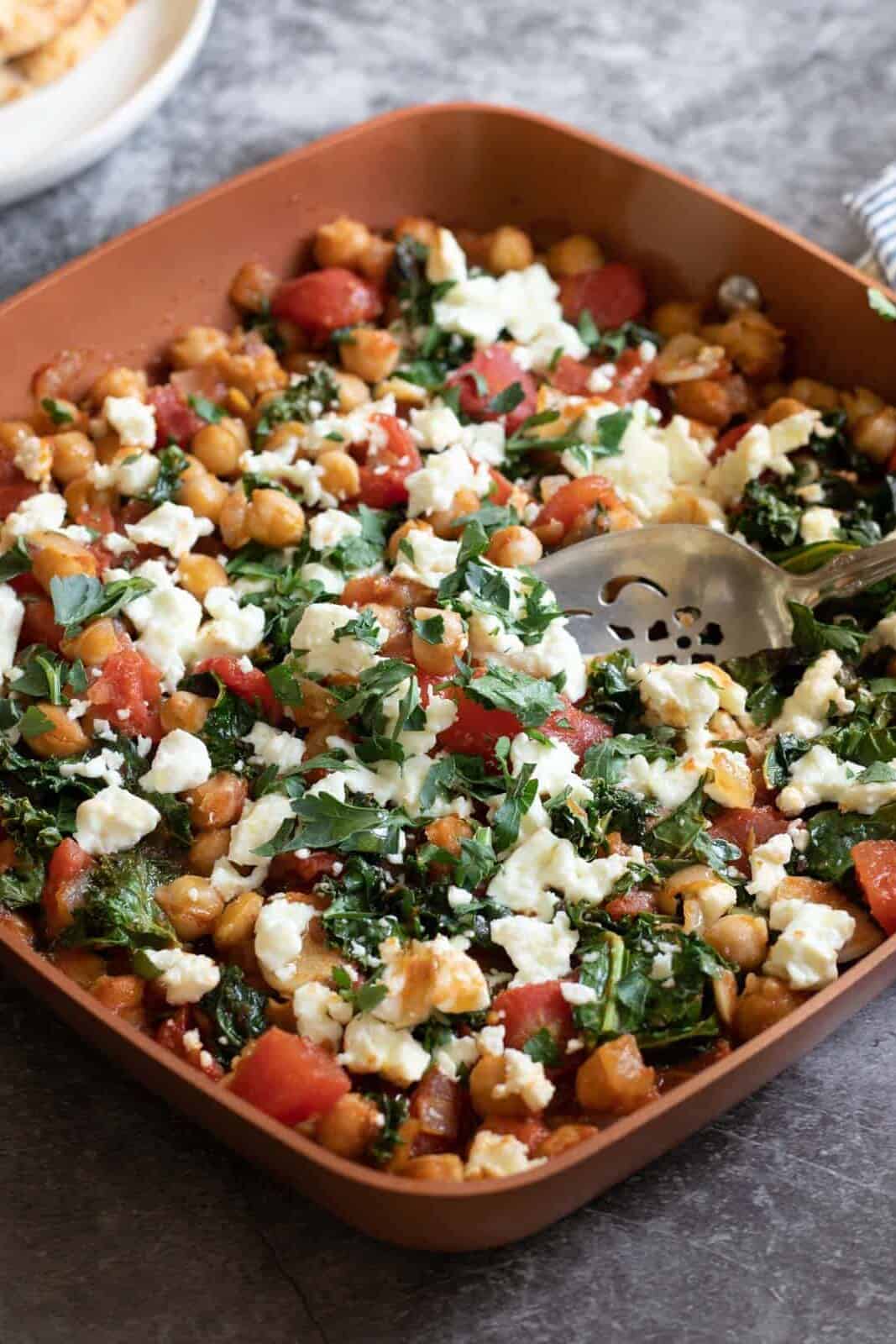 Overhead shot of a chickpea skillet from Parsley and Parm with chickpeas, parsley, tomatoes and feta cheese.