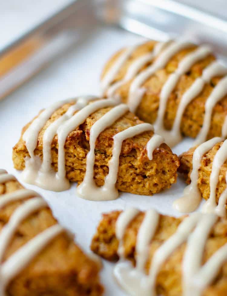 Front view of pumpkin scones on a baking tray with maple glaze from Pretty. Simple. Sweet.