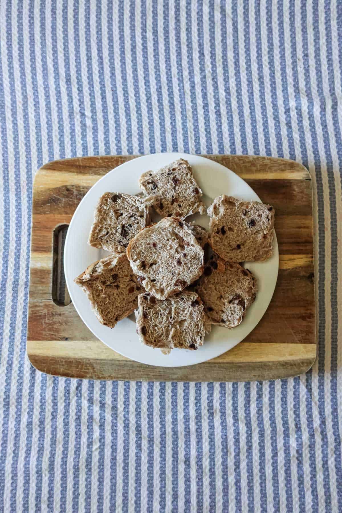 Butter croissant bread slices with chocolate chips on a white plate, on a wooden tray, with a blue striped cloth background, fresh baked croissant bread, chocolate chip bread, breakfast pastry, sweet bread, bakery treat.
