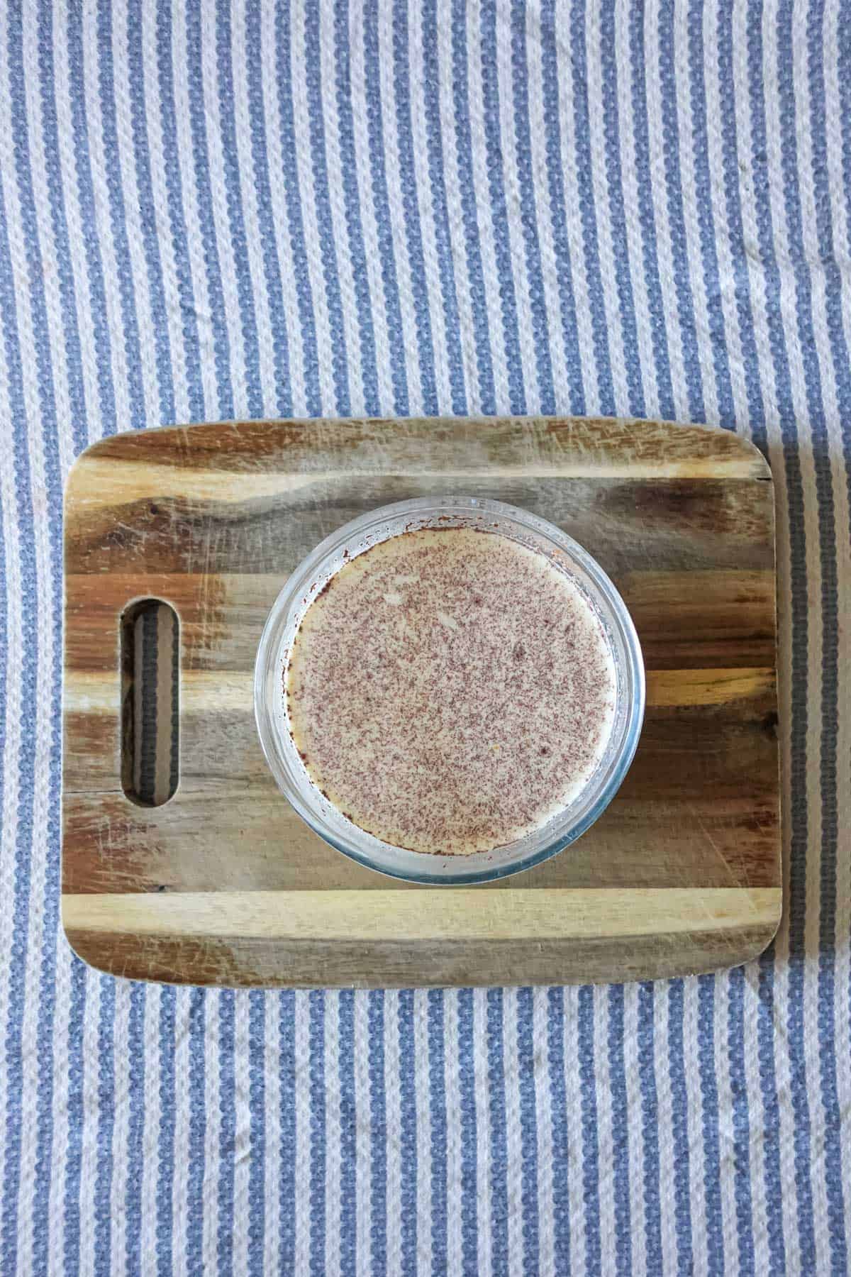 Sweet cinnamon-spiced dessert in a glass bowl on wooden tray, perfect for cozy fall recipes and homemade treats.