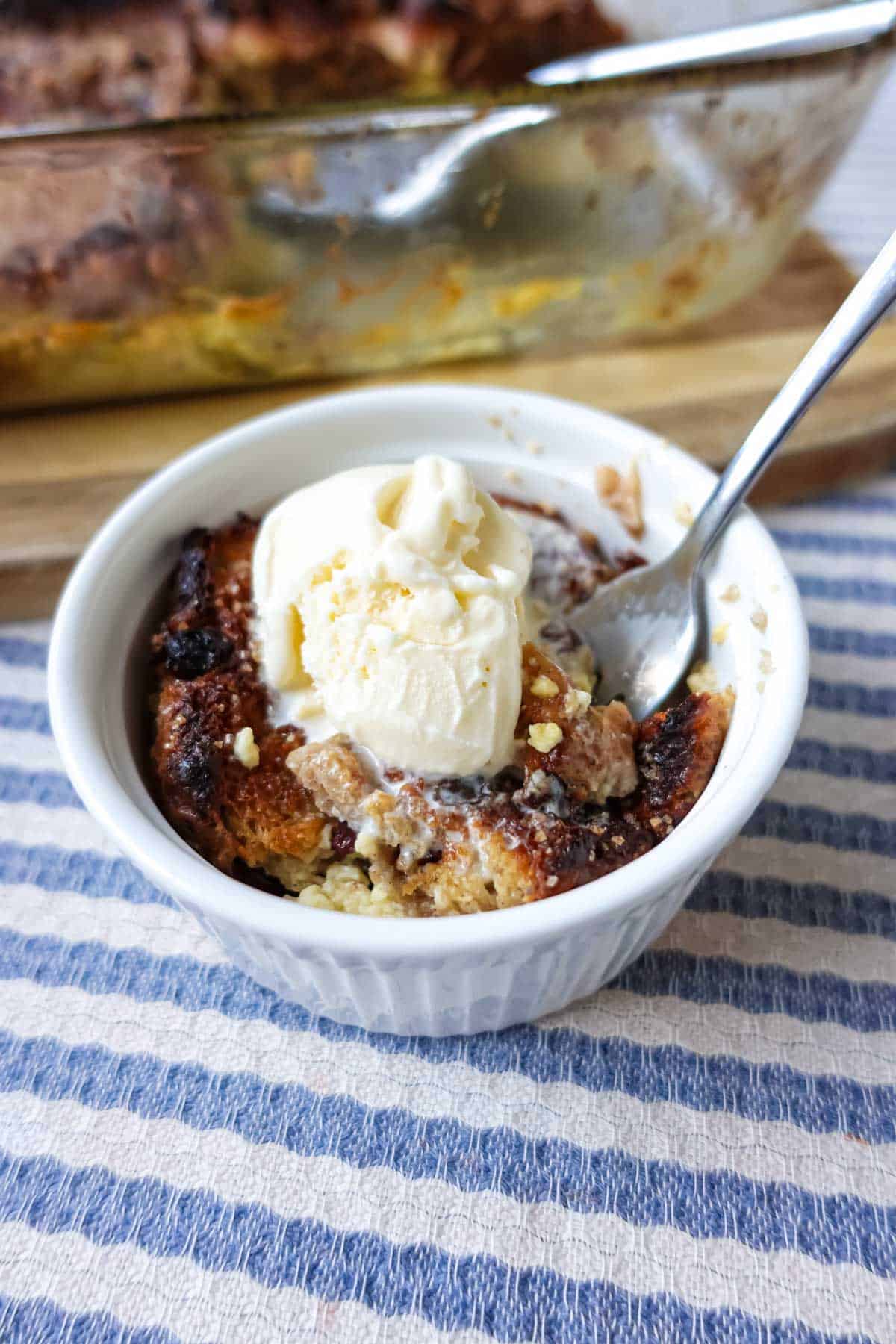 Delicious individual serving of homemade fruit crisp topped with vanilla ice cream, served in a white ramekin on a striped cloth, perfect for fall dessert or a cozy treat.