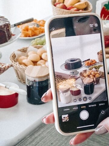 iPhone photographing fresh homemade desserts with fruit, chocolate, and baked goods for a cosy gathering.