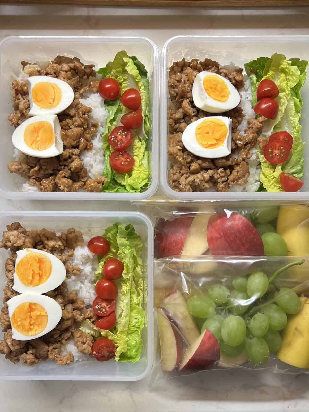 Savoury ground meat lunch containers with boiled eggs, cherry tomatoes, lettuce, and rice