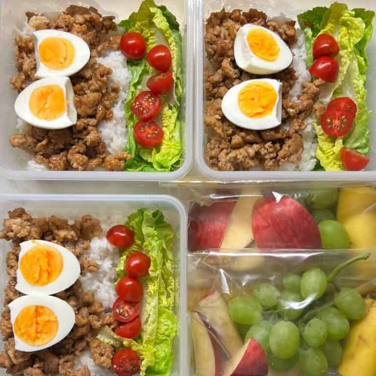 Savoury ground meat lunch containers with boiled eggs, cherry tomatoes, lettuce, and rice