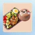 Cobb salad with grilled chicken, boiled egg, and creamy dressing with chocolate and protein pudding in a glass.