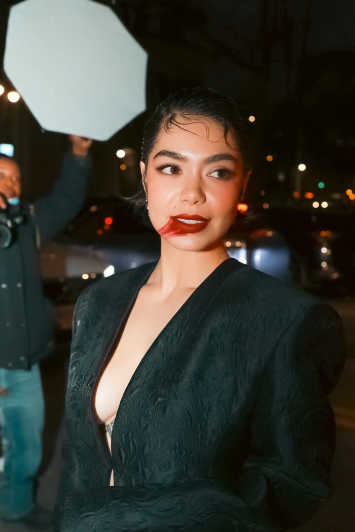 Close-up of guest in dramatic black blazer and bold red lipstick during NYFW street style moment