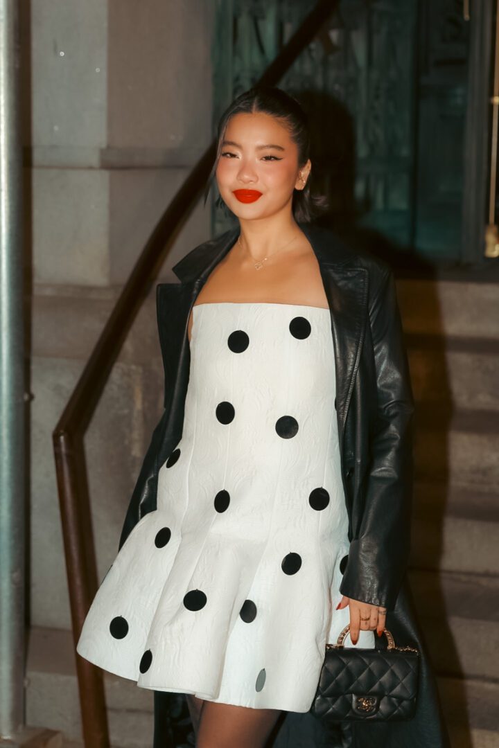 ashion-forward woman in polka dot strapless dress and leather jacket outside NYFW venue