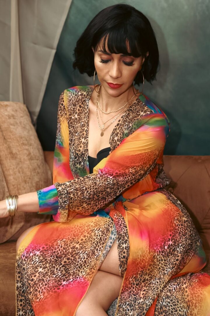 A graceful portrait of a woman in a vibrant, leopard-print robe with gold accessories. Her soft expression and poised posture exude elegance and confidence.