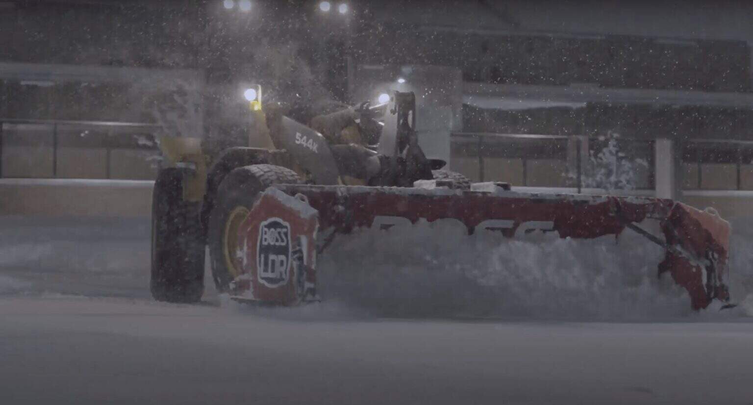 Snow plow clearing snow during winter storm in an urban area, ensuring safe roads and travel conditions.