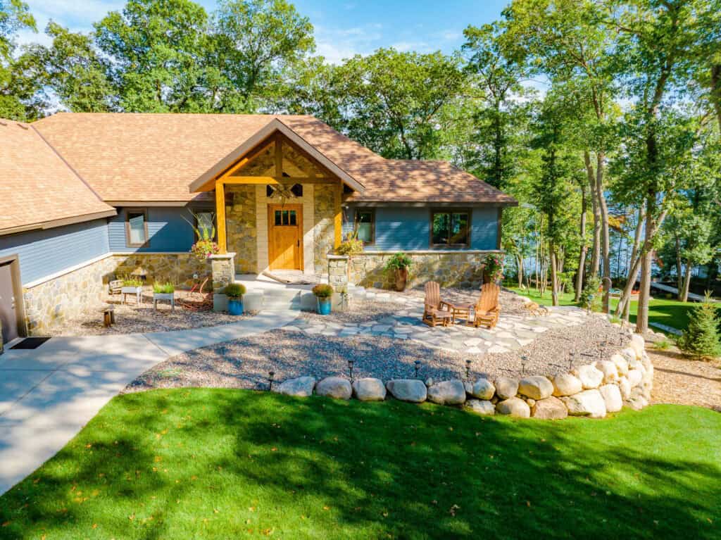 Lush green lawn surrounding a modern house with stone and wood accents, perfect for landscape and lawn care.