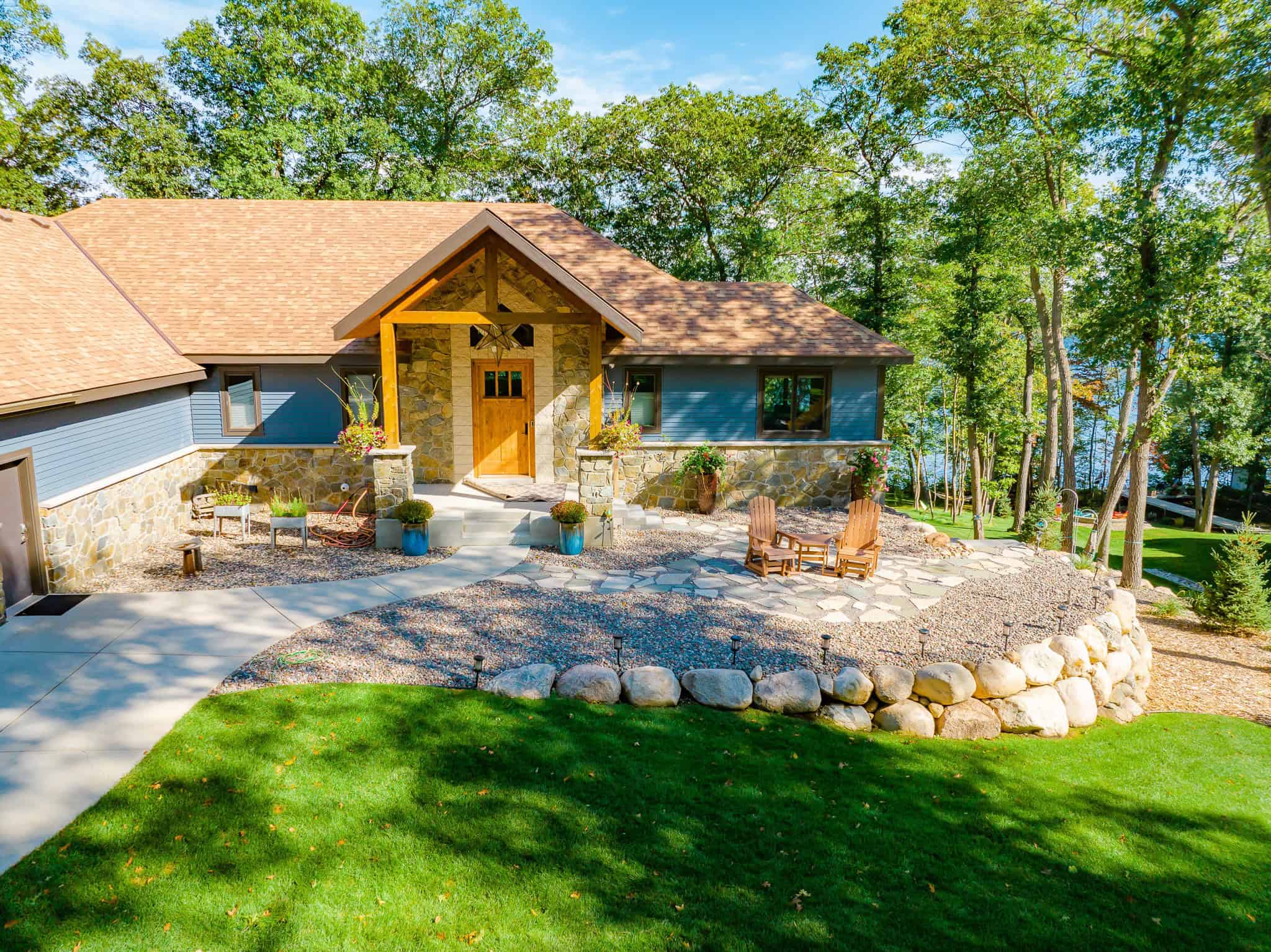 Lush green lawn surrounding a modern house with stone and wood accents, perfect for landscape and lawn care.
