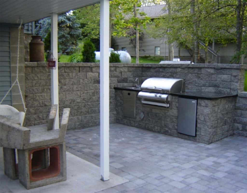 Relaxing outdoor kitchen with built-in grill and stone patio for backyard entertaining.